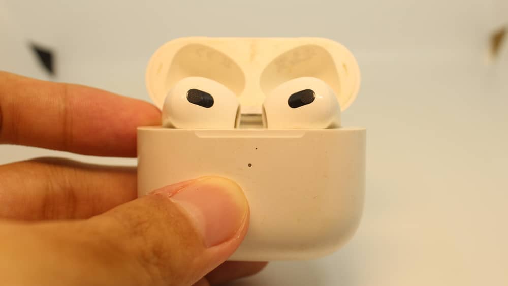 Primer plano de los Apple AirPods Pro 3 en su estuche de carga abierto, sostenido por una mano, mostrando su diseño.